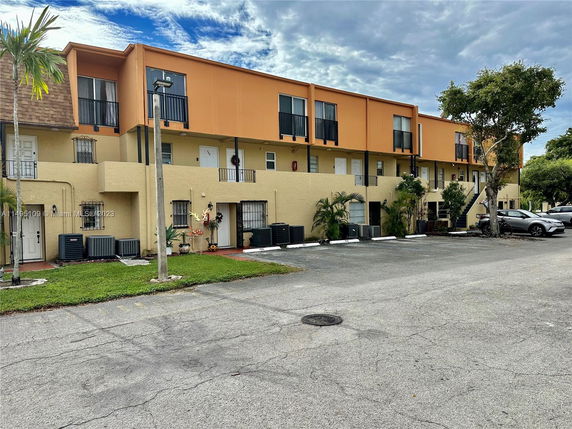 Front view of a multi-story apartment building with parking in front.