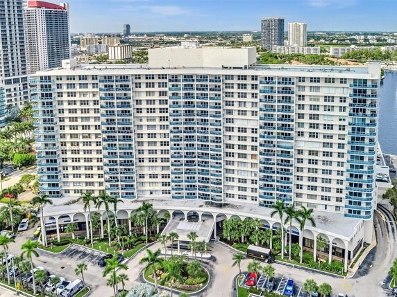 Front view of a multi-story apartment building with balconies and parking area.