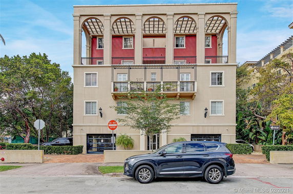 Front view of a multi-story building with balconies and arched features.