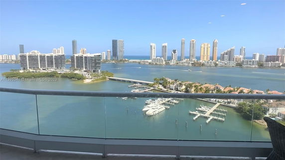 Panoramic view of water and high-rise buildings seen from a balcony.