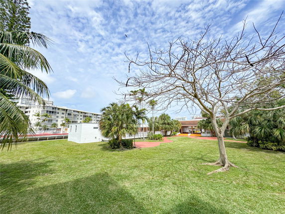 View of surrounding area with a multi-story building and grassy lawn.