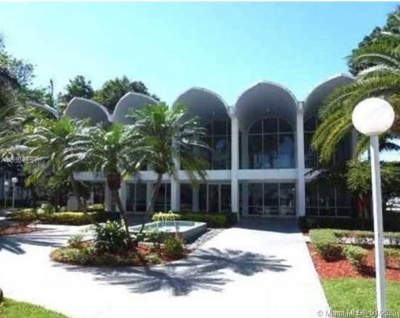 Front view of a unique two-story building with arched windows and a landscaped entrance.