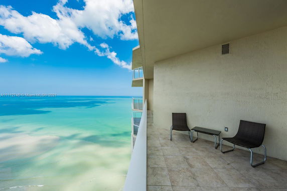 Balcony view overlooking the ocean with seating.