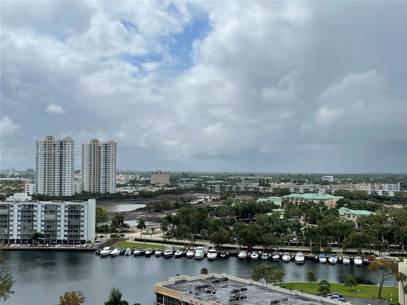 Panoramic view of a cityscape with high-rise buildings and a row of moored boats by a waterway.