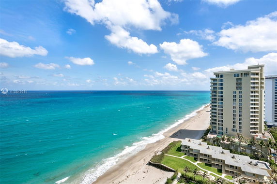 View of the oceanfront with a tall building and sandy beach.