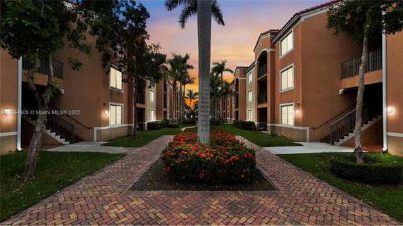 Front view of a multi-story apartment complex with staircases and landscaped pathway.