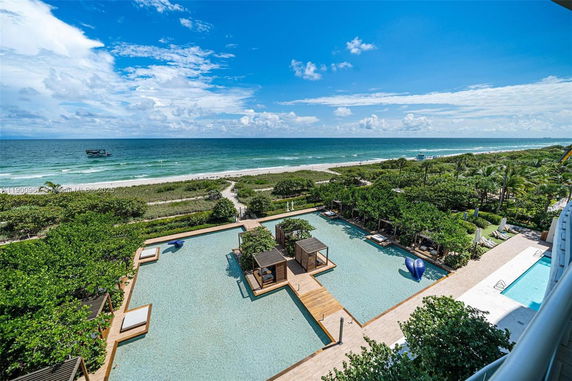 Wide angle view of a beachfront with a swimming pool area and ocean in the background.