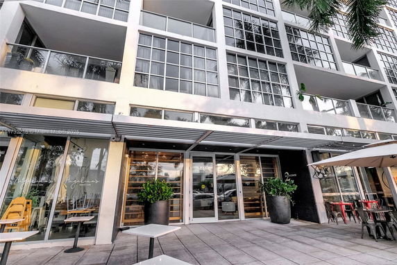Front view of a modern building with large glass windows and outdoor seating.