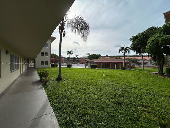 View of buildings and green lawn area with palm trees.