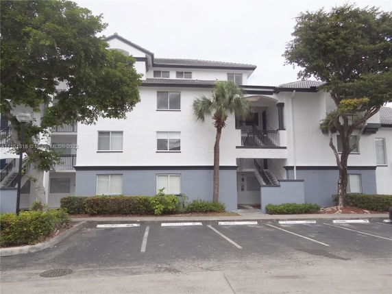 Front view of a multi-story residential building with a light-colored facade and multiple windows.