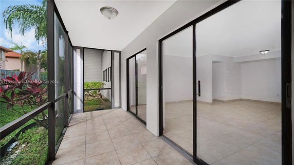 View from a covered patio area with glass doors, showing surrounding garden and exterior walls.