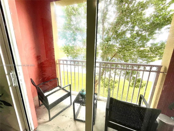 View from a small balcony with chairs overlooking trees and grass.