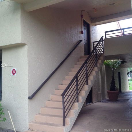 Exterior view of a building entrance with a staircase leading to an upper floor.