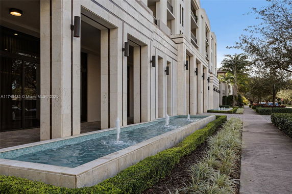 Front view of a modern multi-story building with a row of columns and a fountain.