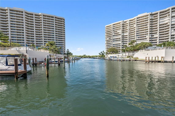 View of two tall residential buildings beside a waterway with boats docked alongside.