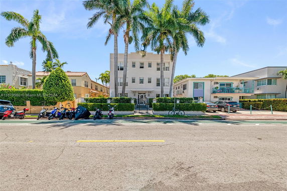 Front view of a multi-story building with a gated entrance and palm trees.