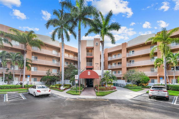 Front view of a multi-story residential building with balconies and an entrance canopy.