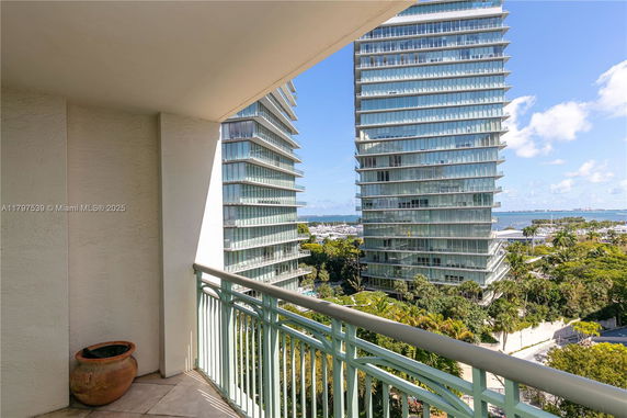 Panoramic view from a balcony overlooking modern glass buildings and a distant body of water.
