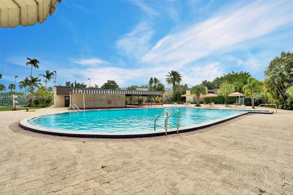 Outdoor swimming pool area with surrounding trees and seating spaces.