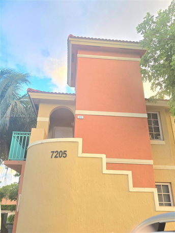 Front view of a two-story building with stucco exterior and decorative stairway.