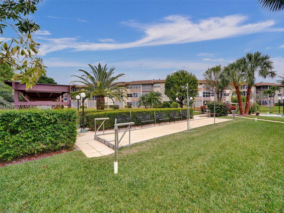 View of a garden area with benches and a walkway in front of residential buildings.