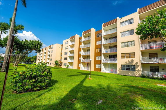 Front view of a mid-rise apartment building with balconies and brown accents.