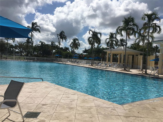Outdoor swimming pool with surrounding lounge chairs and palm trees.