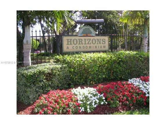 Signage for Horizons, a condominium, surrounded by greenery and flowers.
