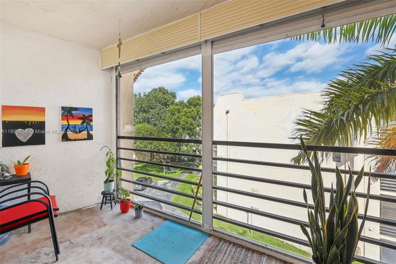 View from a balcony with plants, railing, and partial street scene visible.