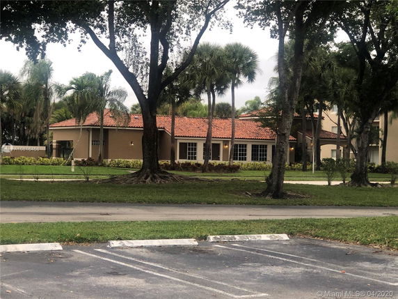 View of a building with a red-tiled roof partially obscured by trees.