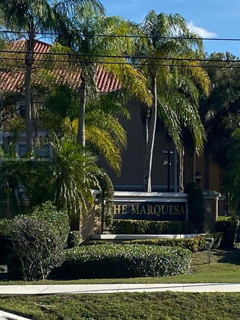 Front view of a building with a sign labeled 'The Marquesa' surrounded by palm trees.
