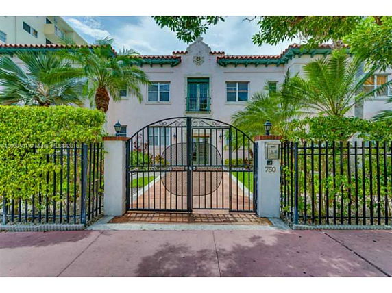 Front view of a two-story house with an ornate gate and palm trees in the foreground.