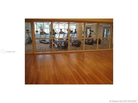 Indoor gym area with exercise equipment and wooden flooring.