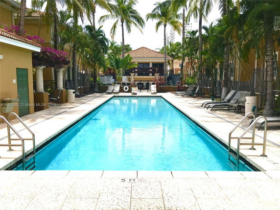 Outdoor swimming pool surrounded by tropical plants and lounge chairs.