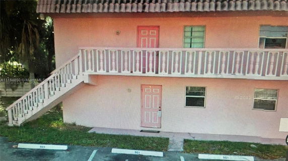 Front view of a two-story building with exterior stairs and pink doors.