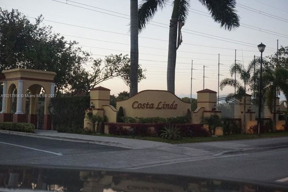 Front view of a gated community entrance with 'Costa Linda' sign.