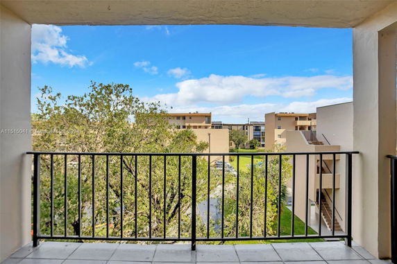 View from a building balcony overlooking surrounding apartment buildings and trees.