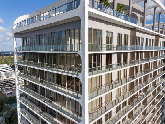 Front view of a modern multi-story building with large glass windows and balconies.