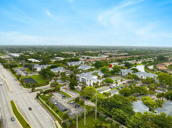 Aerial view of a residential area with multiple white apartment buildings surrounded by greenery and roads.