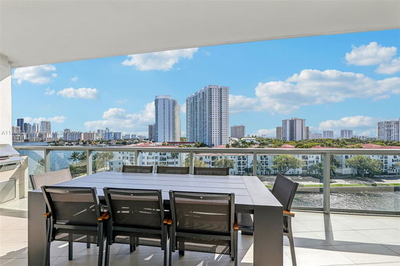 Panoramic view from balcony showing a table and chairs with city skyline in the background.
