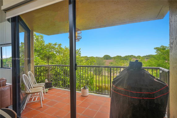 View from a balcony overlooking trees and rooftops in the distance.
