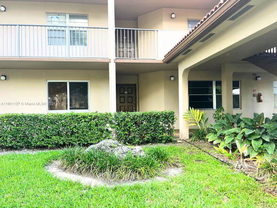 Front view of a two-story building with balconies and plants.