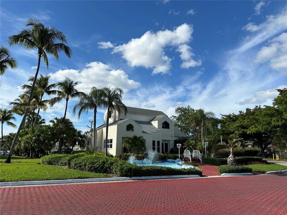 Front view of a two-story house with a gabled roof and a fountain in the foreground.