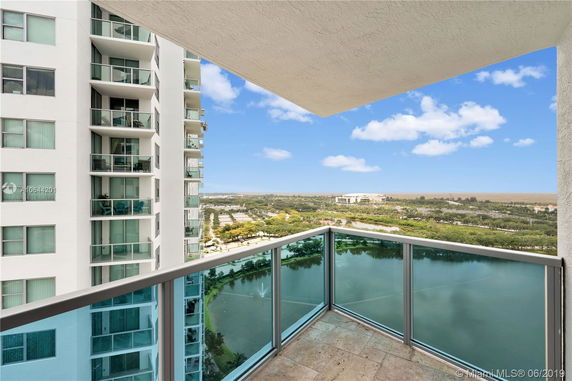 View from a building balcony showing nearby buildings and a scenic landscape.