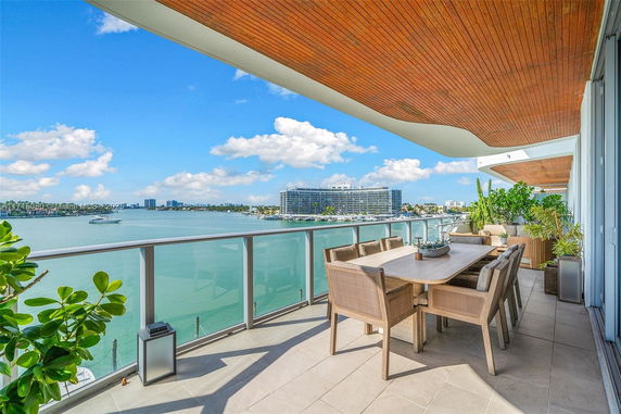 Outdoor balcony with dining table offering panoramic view of water and surrounding buildings.