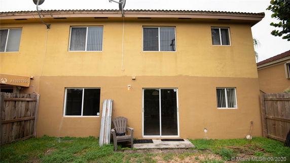Rear view of a two-story house with yellow walls and a sliding glass door.