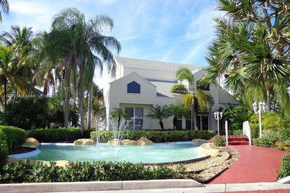 Front view of a house with a pitched roof and a fountain in front.