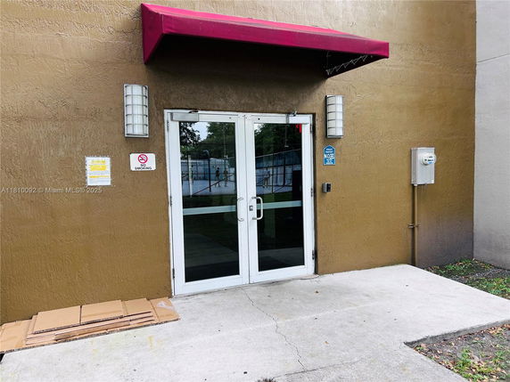 Entrance view of a building with glass doors and a red awning.