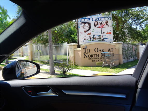 Front view of a gated residential complex with a sign reading 'The Oak at North Miami'.