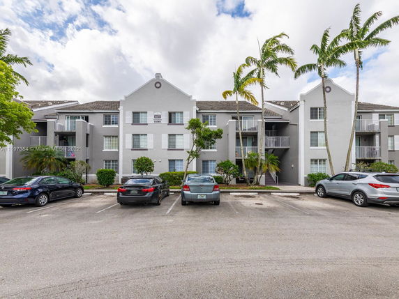 Front view of a multi-story residential building with balconies and parking area.